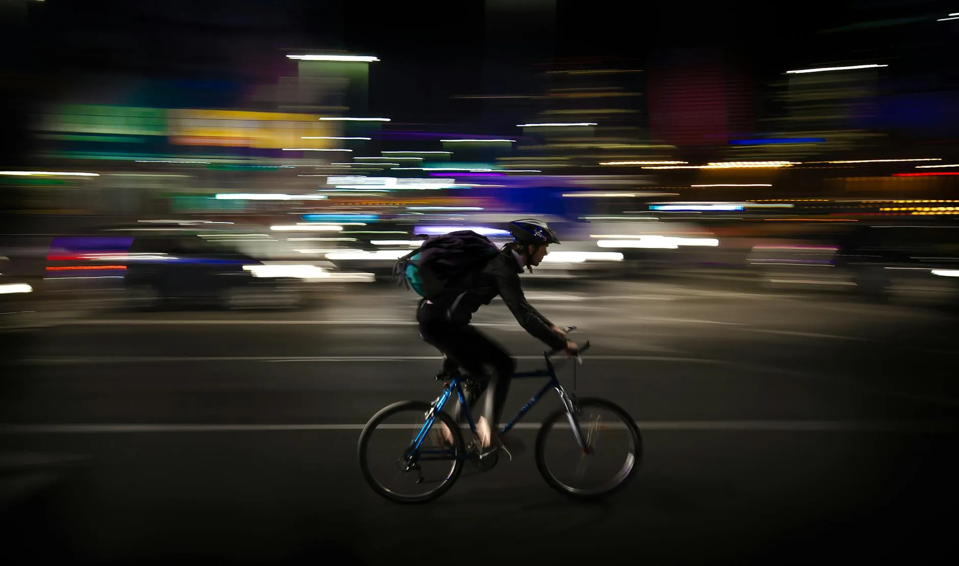 Rowerzysta nocą jedzie szybko przez oświetlone miasto