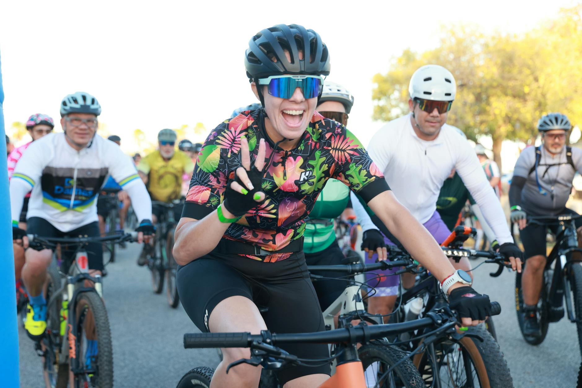 Grupa rowerzystów w kolorowych strojach szykuje się do wspólnego rajdu