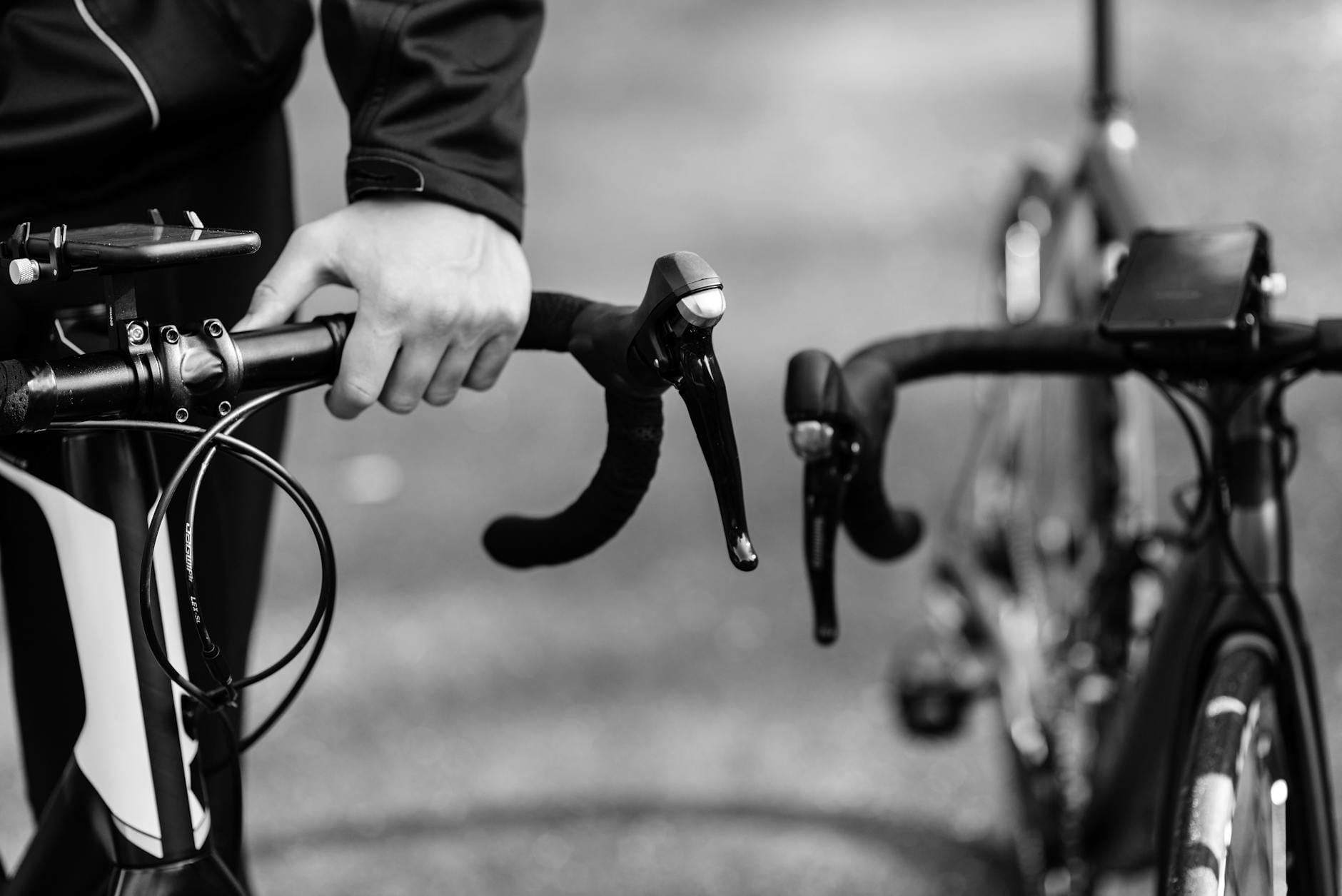 Kolarz trzyma kierownicę szosowego roweru w czarno-białym ujęciu