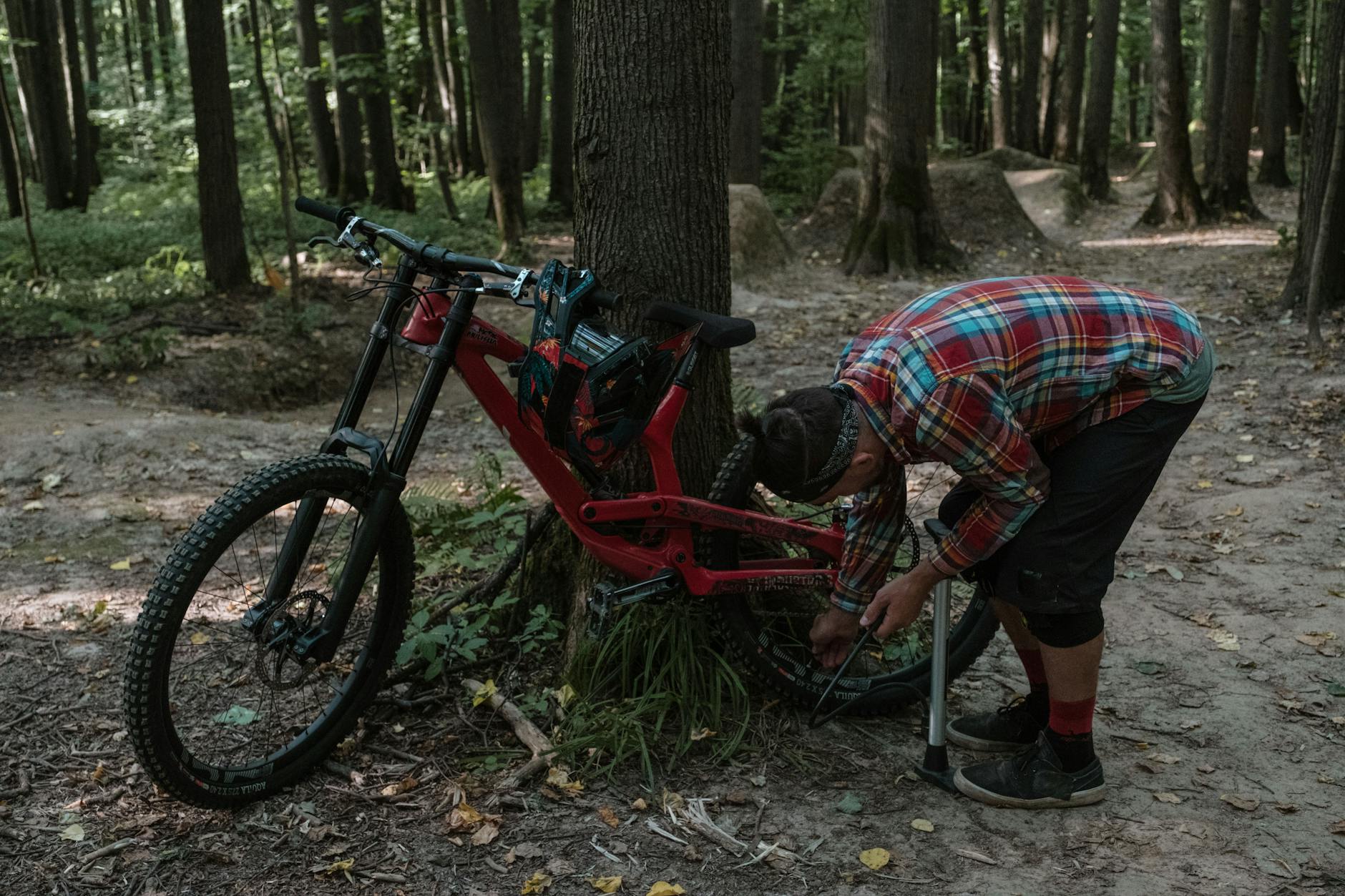 Mężczyzna naprawia rower w letnim lesie podczas wyprawy rowerowej