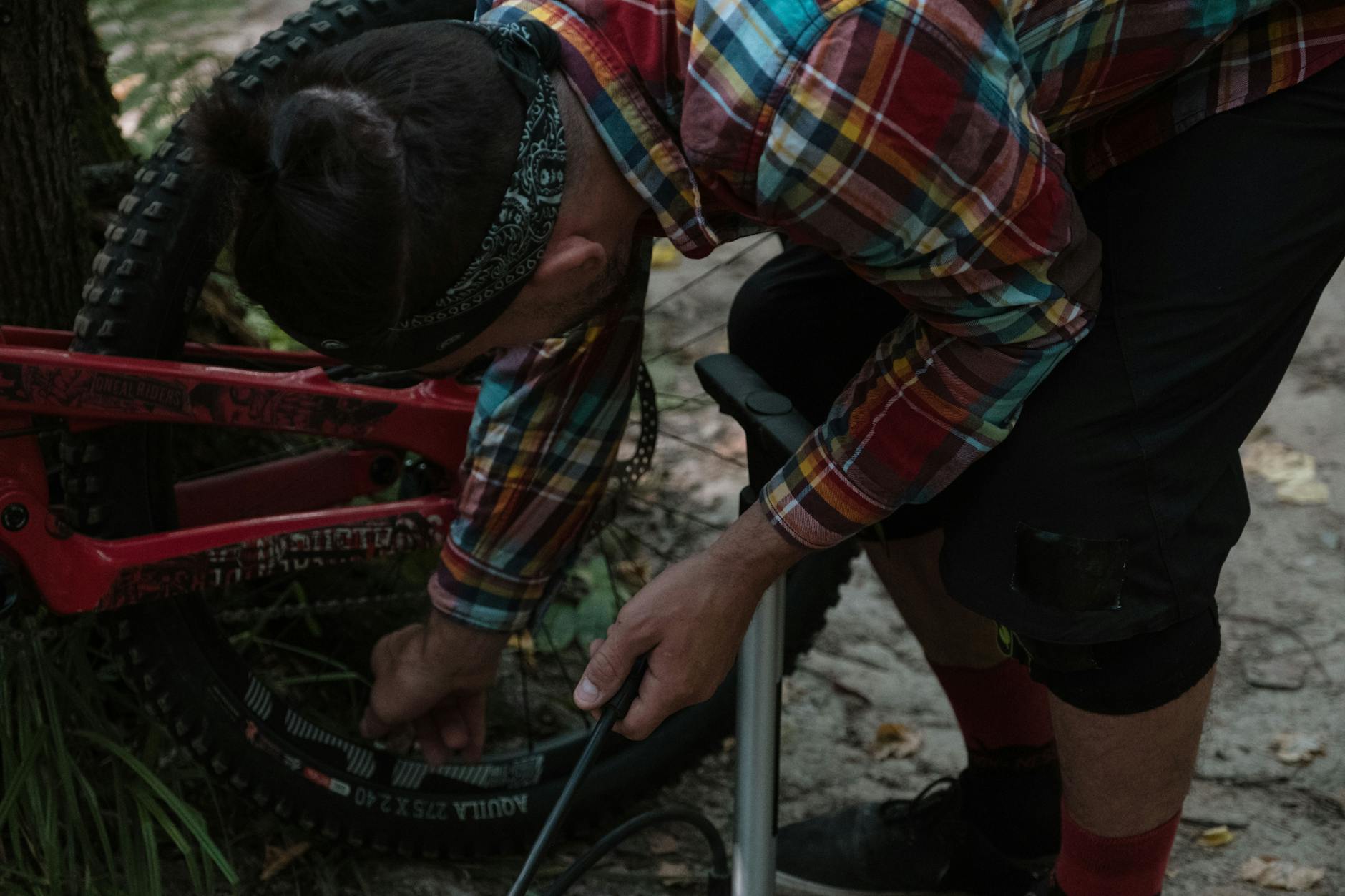 Rowerzysta pompuje oponę górskiego roweru mini pompką w lesie