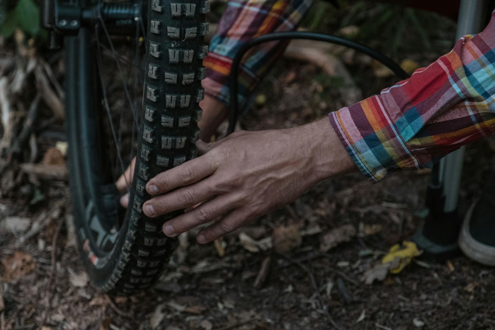 Rowerzysta pompuje oponę roweru górskiego w leśnym otoczeniu