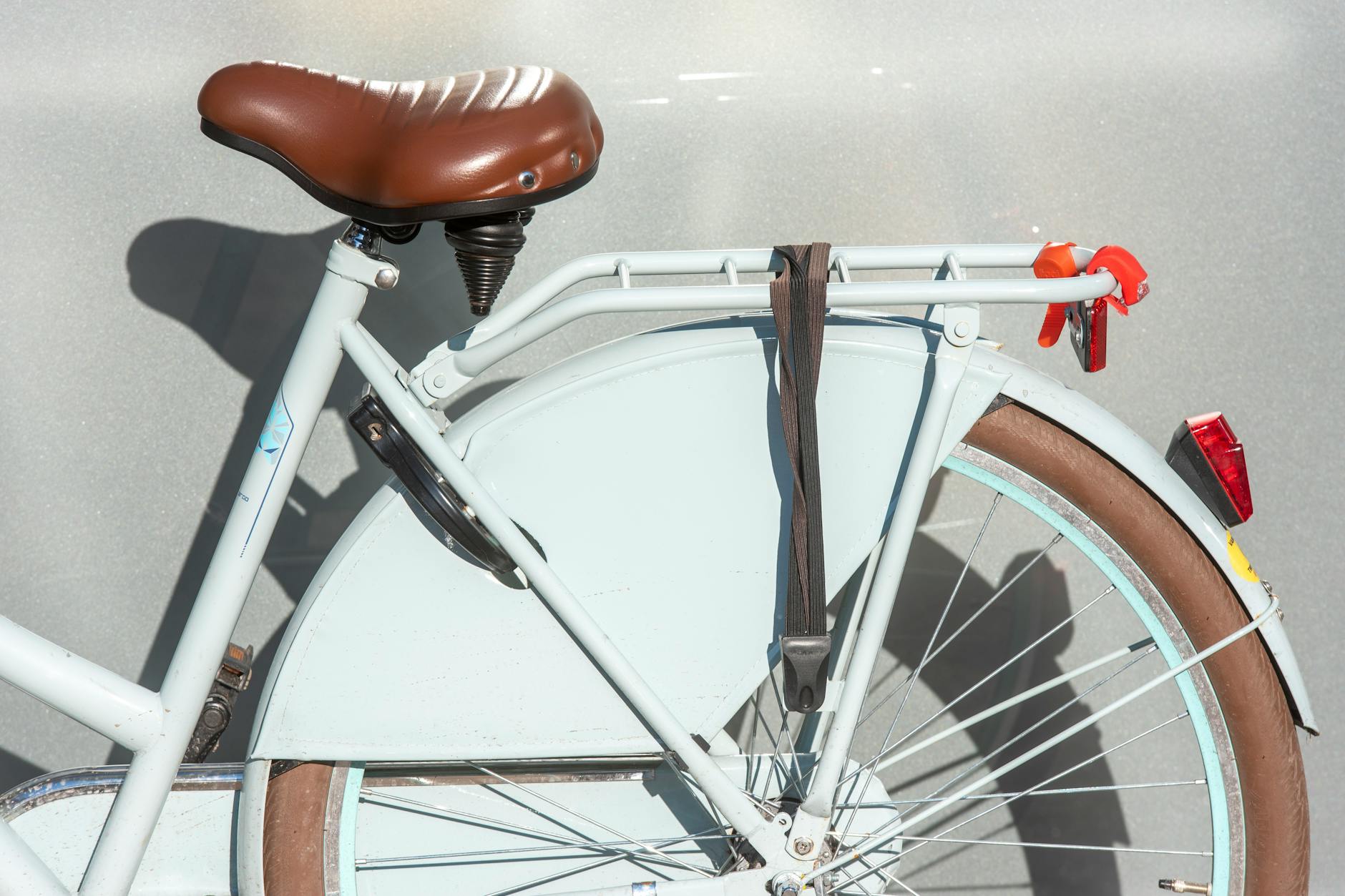 Zbliżenie na tylny bagażnik i brązowe siodełko roweru miejskiego