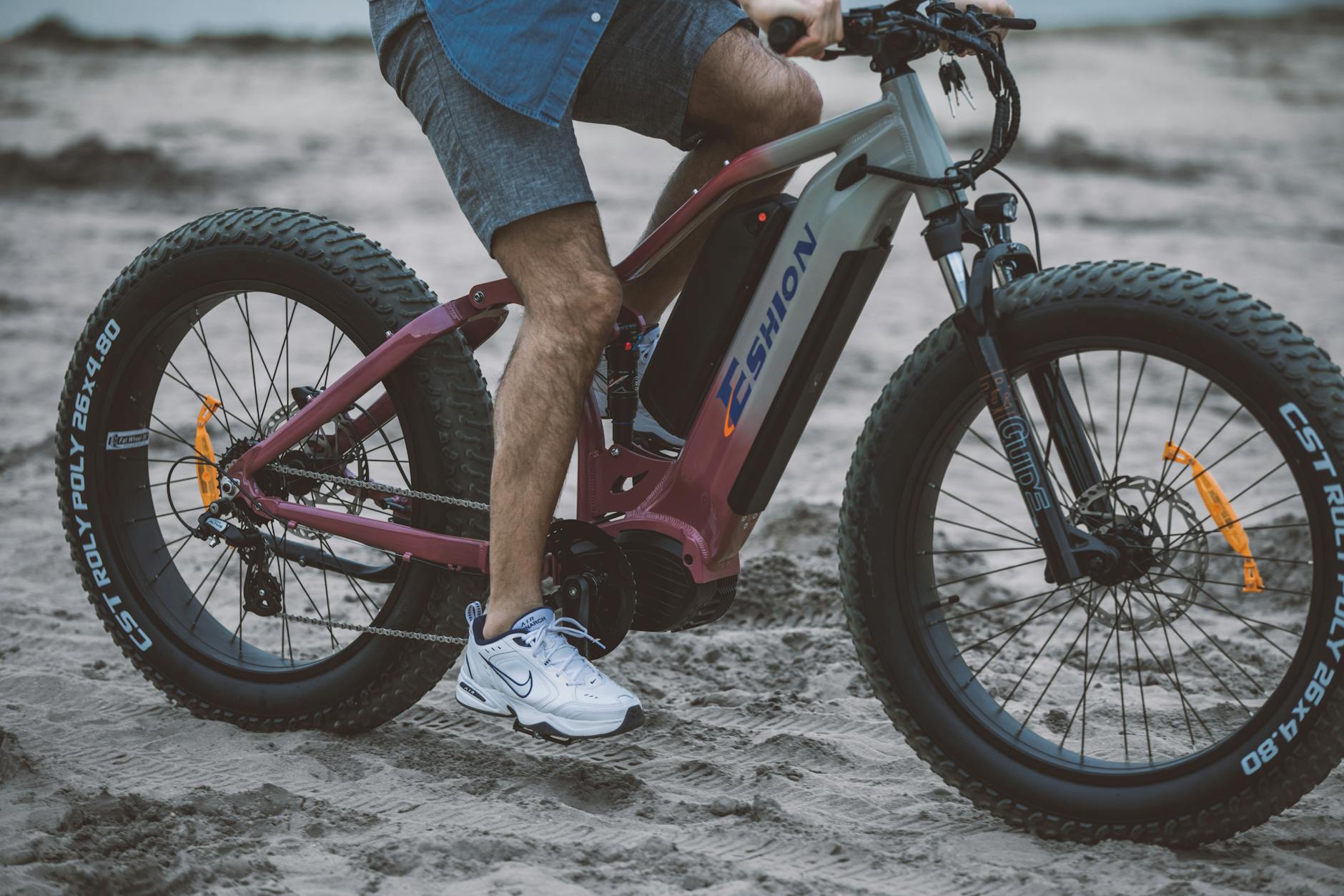 Mężczyzna jedzie e-rowerem z grubymi oponami po piaszczystej plaży