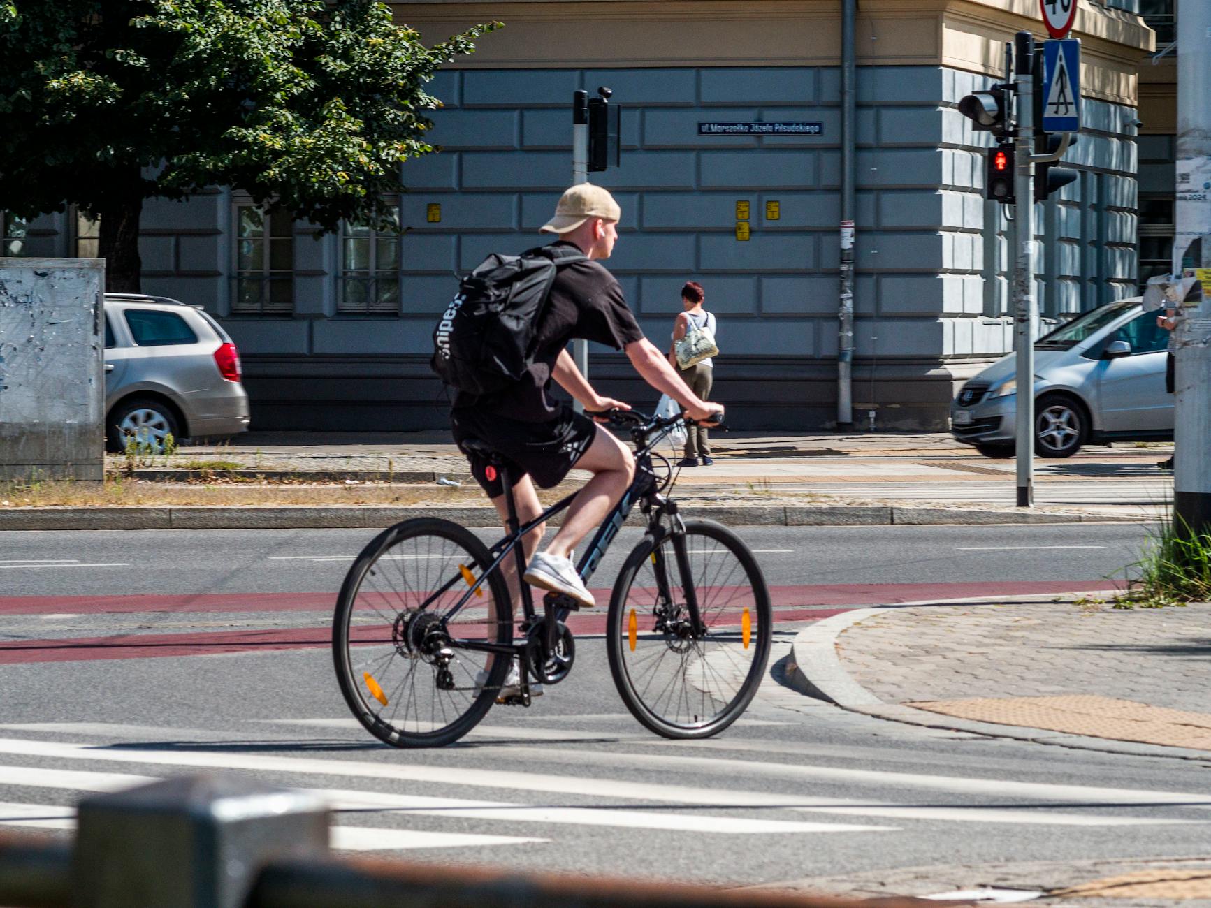 Mężczyzna na rowerze gravelowym przejeżdża przez miejskie skrzyżowanie