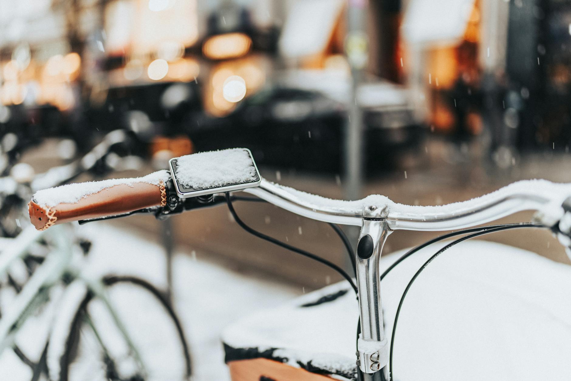 Ośnieżona kierownica roweru na zimowej miejskiej ulicy
