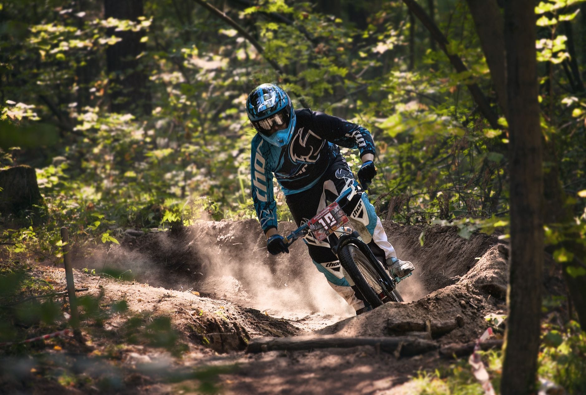 Rowerzysta enduro jedzie szybko po stromym, leśnym szlaku zjazdowym