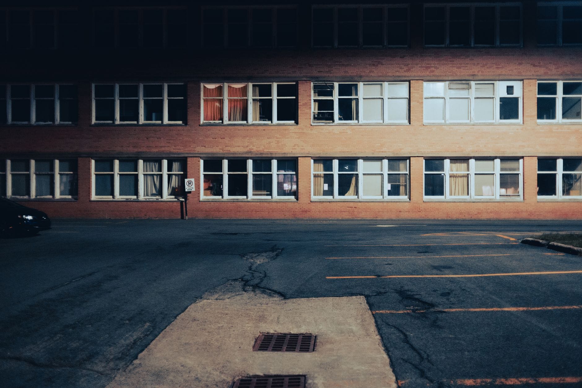Opuszczony parking nocą przy ceglanej ścianie budynku Opuszczony parking nocą przy ceglanej ścianie budynku