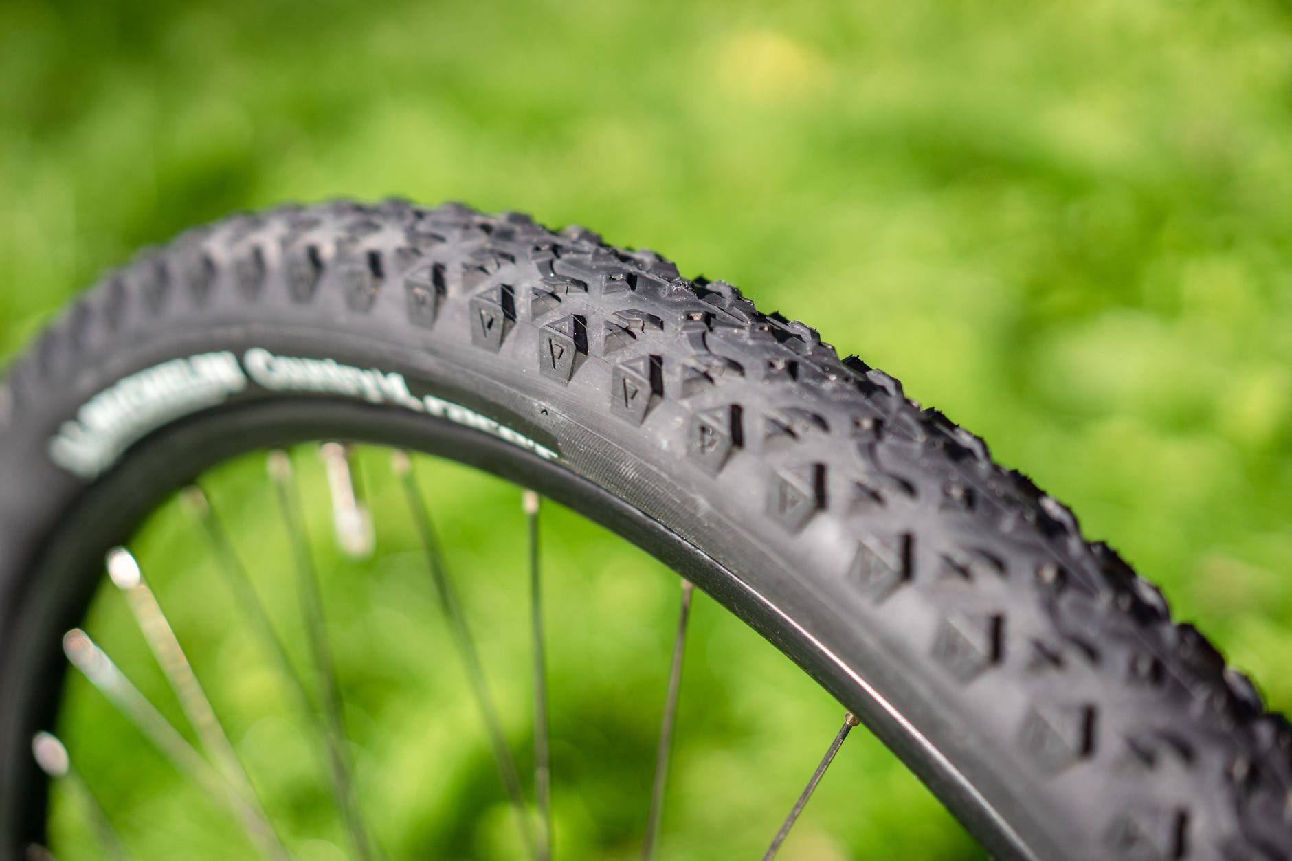 Bieżnik opony MTB w zbliżeniu na tle rozmytego krajobrazu