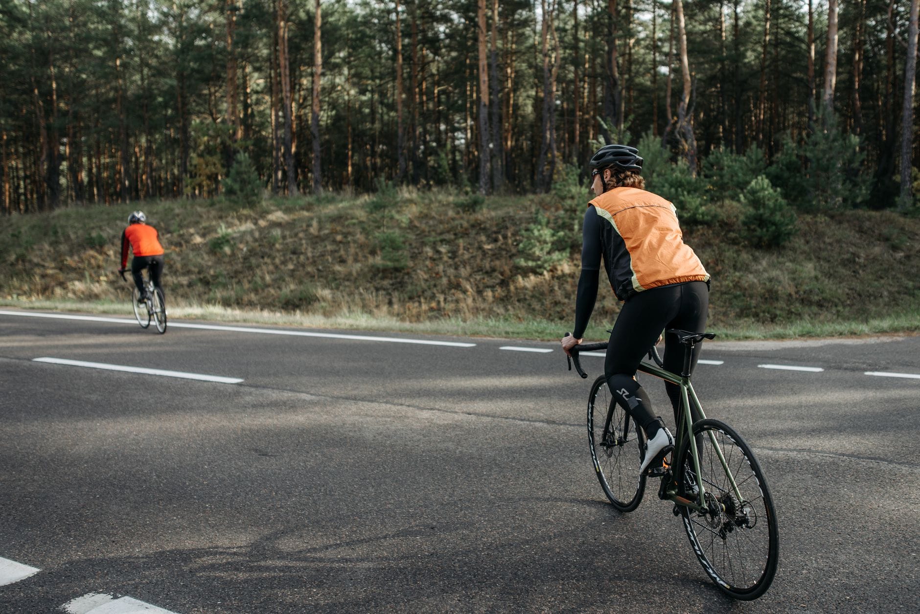 Odblaski, które działają: gdzie je przykleić na rowerze i kasku? Dwóch rowerzystów w odblaskowych kamizelkach na leśnej drodze
