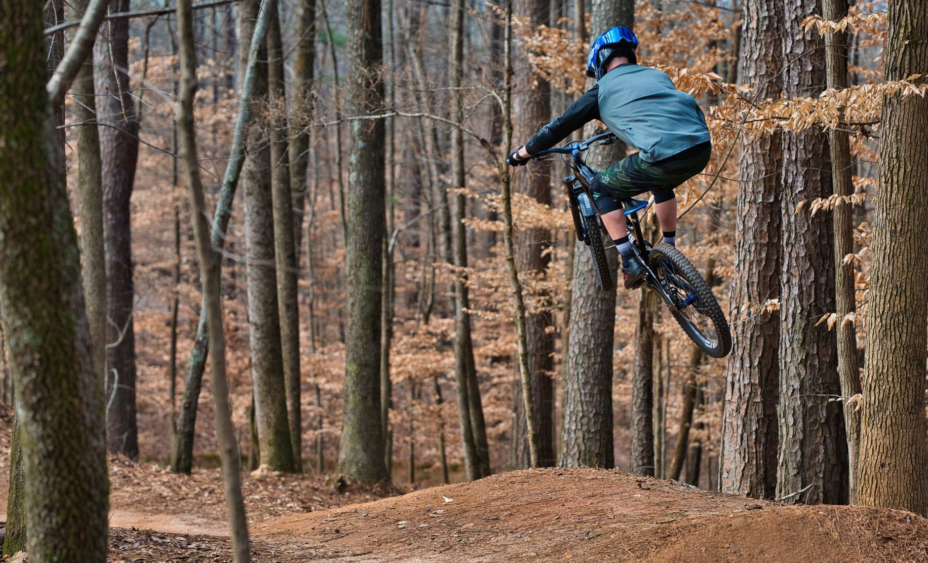 Rowerzysta MTB skacze na hardtailu między drzewami w lesie