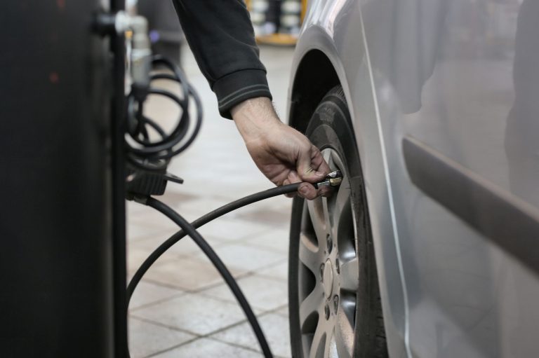 Mechanik pompuje oponę samochodową w warsztacie