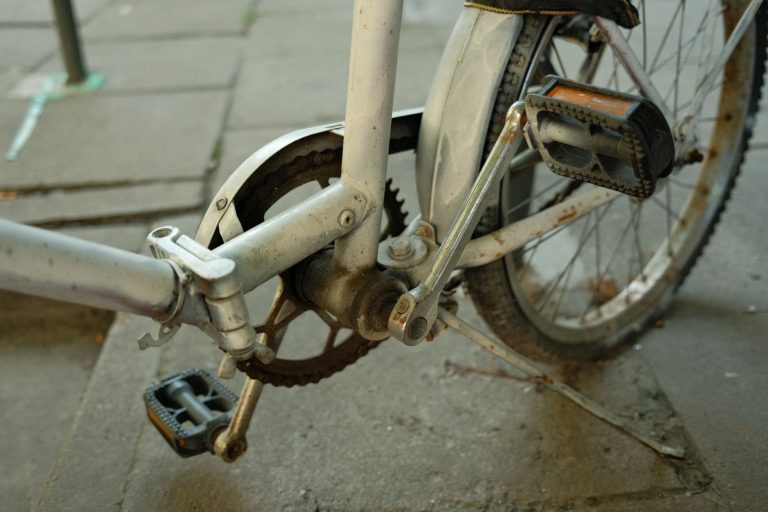Zardzewiała korba i pedał starego roweru w miejskim otoczeniu